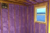 purple spray foam insulation applied in exposed wooden framing of home