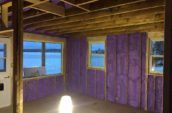 purple spray foam insulation applied to walls of cabin between wooden framing