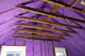 purple spray foam insulation applied on walls and roof between wooden beams