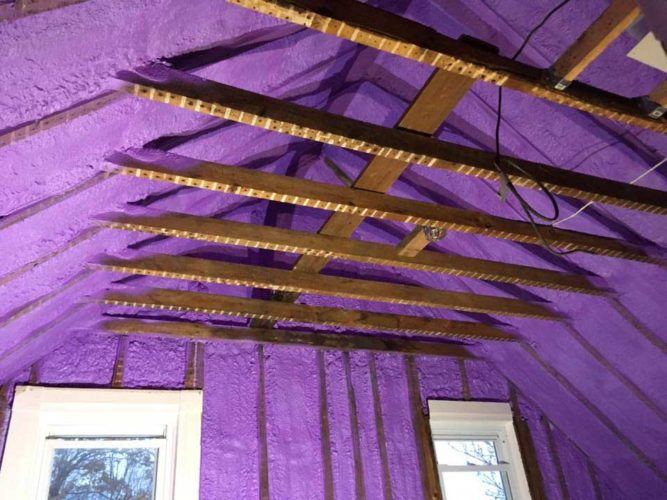 purple spray foam insulation applied on walls and roof between wooden beams