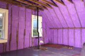 purple spray foam insulation covering walls and roof of farm house