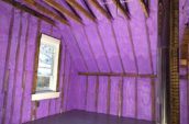 purple spray foam insulation covering walls and roof of farm house