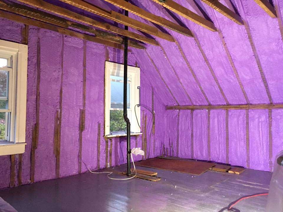 purple spray foam insulation covering walls and roof of farm house
