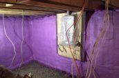 purple spray foam insulation in basement walls with wires hanging from ceiling