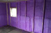 Purple spray foam insulation on the framed walls of an old outbuilding